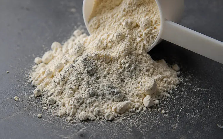 A scoop of protein powder spilling, a dull gray tint through part of it