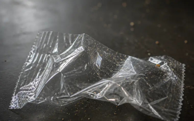 A crumpled clear plastic wrapper with faint flecks scattered around it